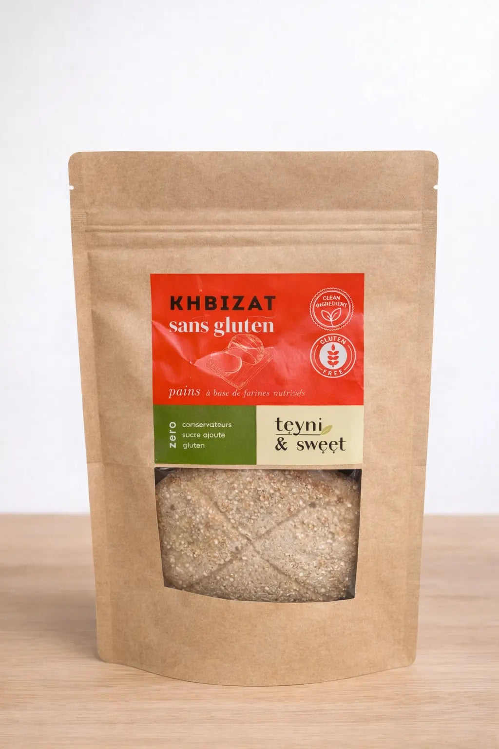 Sachet de khbizat / pains sans gluten Teyni & Sweet, petits pains marocains healthy présentés sur une planche en bois avec graines et éléments naturels autour.