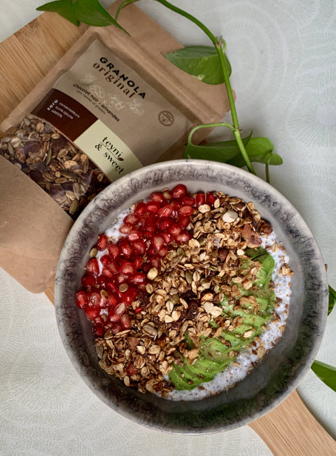 Bol de petit-déjeuner au yaourt garni de granola croustillant, fruits frais et graines.